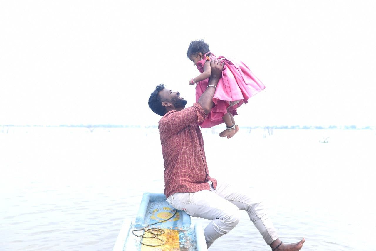 Father lifting child in pink dress at beach
